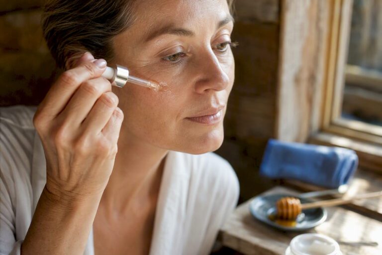 Donna che applica il siero sui pori della pelle matura
