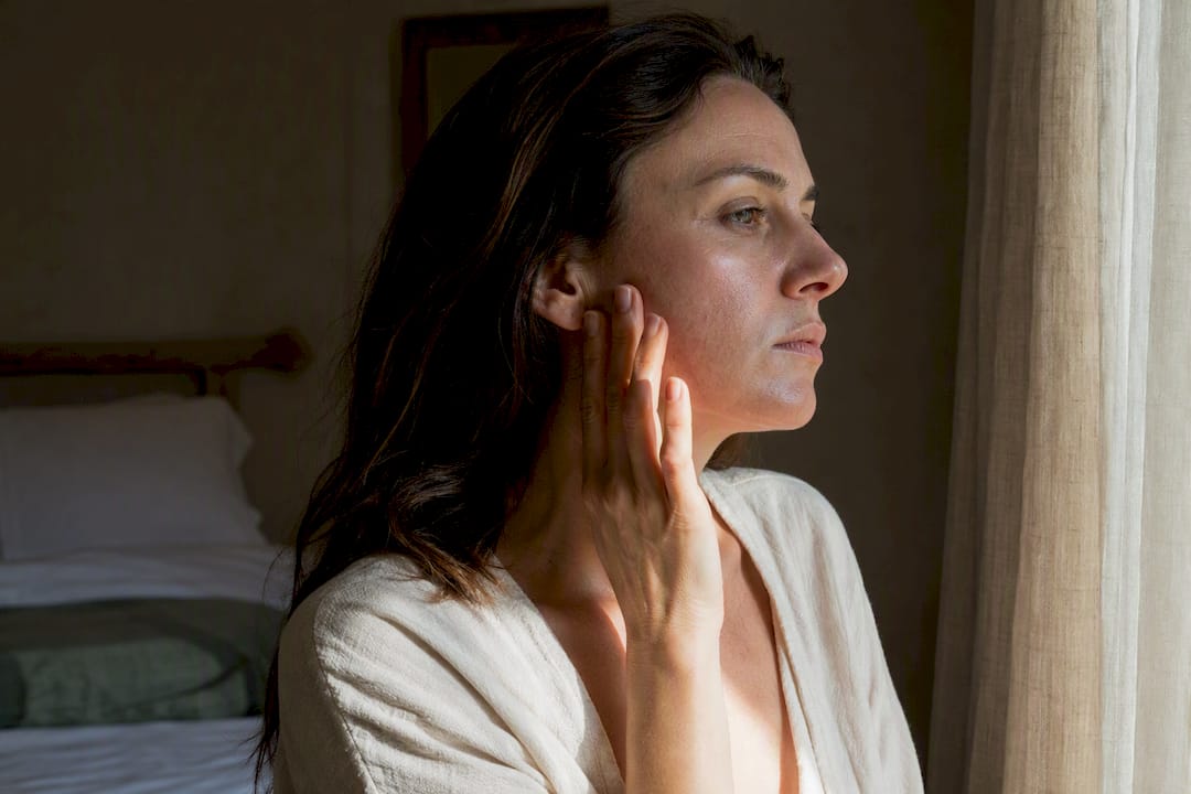 Donna fissa la pelle opaca vicino alla finestra